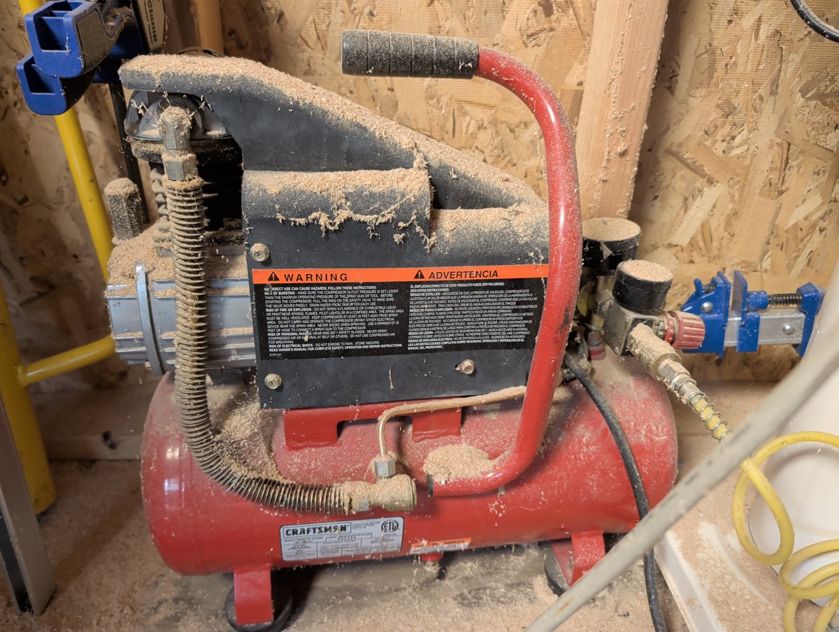 Red air compressor covered in sawdust used condition